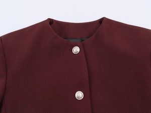 Detail of round neck burgundy jacket featuring textured fabric and silver metal buttons