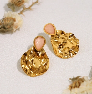 Macro detail of gold hammered metal earrings with teardrop pink aventurine stones