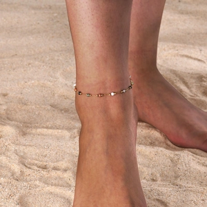 Golden beaded anklet with colorful natural stones on a beach setting