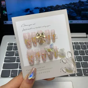 Detail of pink gradient press-on nails with glitter, bows and 3D butterfly charms