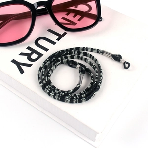 Detail of bohemian black and white braided eyewear strap with adjustable rubber ends