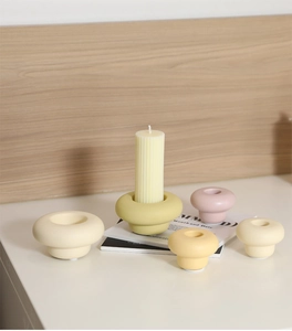 Detailed view of modern ceramic candle holder with a white pillar candle on a table