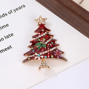 Macro shot of red enamel Christmas tree brooch with colorful rhinestones on gold base