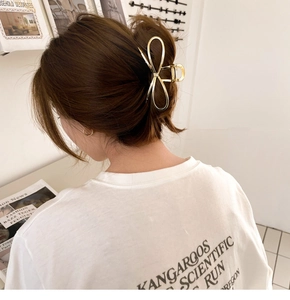 Close-up of golden metal bow hair claw clip styled on a woman's brown hair