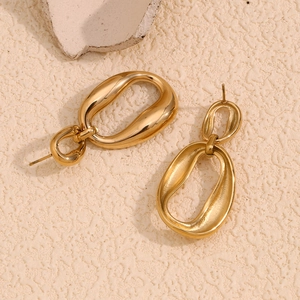 Detail shot of golden irregular geometric earrings on a textured stone surface