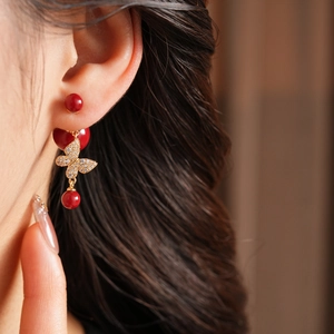 Detail of vintage butterfly earrings with gold plating, red pearls, and micro-set zircons