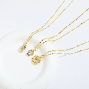 Detail of gold tree of life pendant and zircon necklaces on white ceramic plate