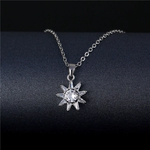 Collier avec pendentif tournesol en acier titane et zircons sur fond sombre mat