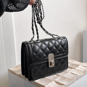 Detail of black quilted leather chain bag with silver clasp and metallic strap