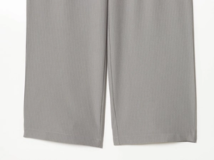 Detailed close-up of grey pinstripe trousers showing fabric texture and hem stitching