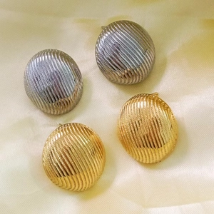 Detailed view of spherical 18K gold and silver stud earrings with parallel striped texture