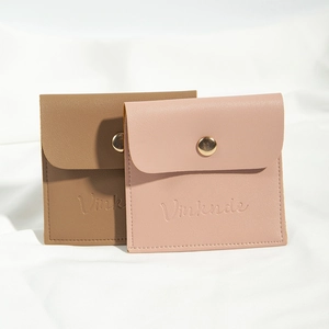 Brown and pink PU leather jewelry pouches with golden metal snap fasteners on white fabric
