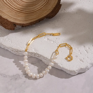 Detailed view of natural freshwater pearls joined with a gold paperclip chain on a stone