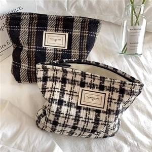 Close-up of checkered tweed cosmetic bags with retro woven label and metal zipper closure