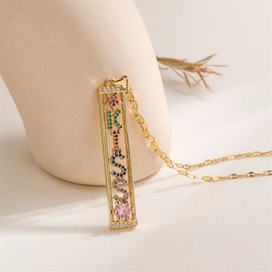Detail of gold necklace with multi-color zircon stones spelling KISS on a ceramic vase