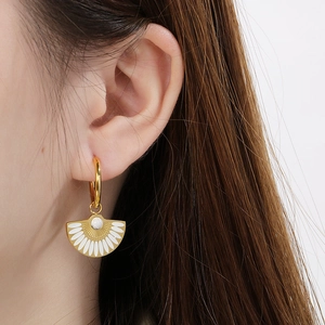 Detailed close-up of vintage fan-shaped earrings with white enamel and marble beads on a model