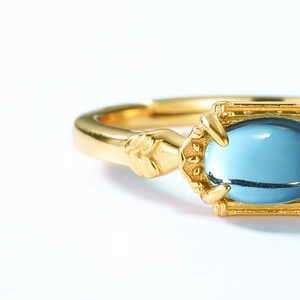 Macro shot of oval blue topaz gemstone set in textured gold vintage ring band