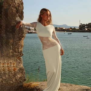 Détail d'une robe en dentelle blanche à manches longues montrant la texture du tissu au bord de mer