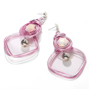 Detail view of handmade wire-wrapped heart pearl earrings with pink gemstones on white base