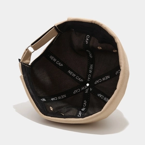 Detail view of beige docker cap featuring black inner lining and NEW CAP reinforcement tape