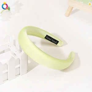 Detail of light green padded headband with a hand made label on a white background
