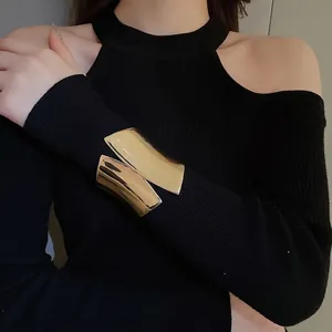 Polished gold wide irregular metal cuff bracelet on model with black knitwear