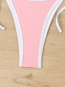 Detail of pink bikini bottom featuring wavy texture and contrast white strap bindings