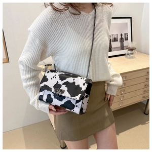 Detail of a cow print square crossbody bag with chain strap and metal clasp closure