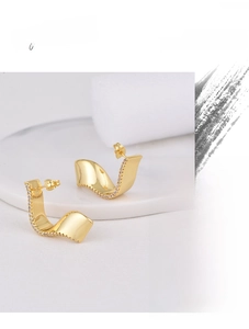 Detailed macro shot of gold plated geometric ribbon earrings with white zircon accents
