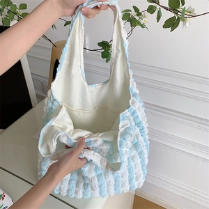 Detail of the inner lining and side pocket in a blue striped bubble fabric tote bag