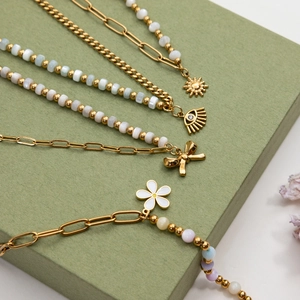 Detail of layered gold bracelets with natural stone beads and charms on a green box