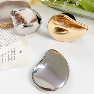 Close-up of liquid metal style gold and silver irregular droplet earrings on an open book