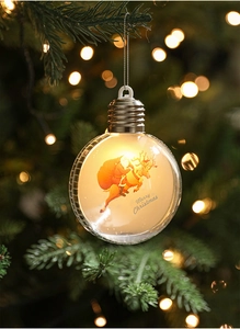 Close-up of glowing Christmas tree ornament with Santa and reindeer silhouette inside