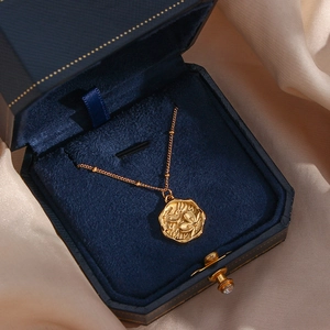 Detail of golden flower relief pendant on a pearl chain inside a velvet jewelry box