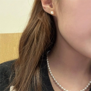 Close-up of minimalist white pearl earrings and matching necklace set on model