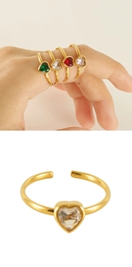 Detail of adjustable gold-finish rings with heart-shaped gemstones in multiple colors