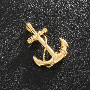 Macro shot of gold pirate anchor pendant with intricate rope detail on black texture