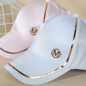 Détail de casquettes en satin rose et blanc avec bordure dorée et logo M métallique