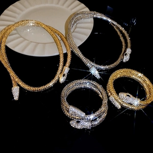 Macro view of crystal-encrusted snake-shaped metal mesh jewelry set in gold and silver