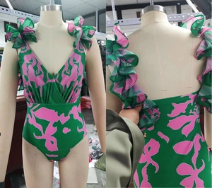Detail of green floral swimsuit featuring ruffled straps and deep V-neck pleated design