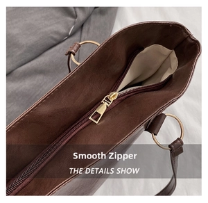 Detail showing the smooth gold metal zipper and stitching on the dark brown tote bag