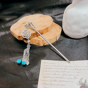 Detail of silver vintage hairpin with hollowed flower and turquoise beaded tassels