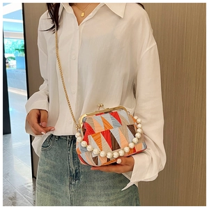 Detail of color-block geometric handbag with faux pearl handle and gold chain strap