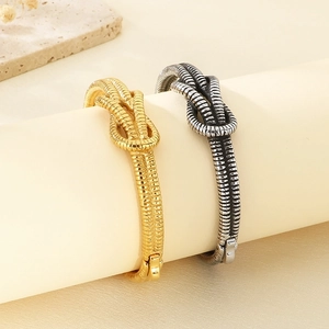 Detail of twisted knot bangles in gold and silver finish with spiral texture on display
