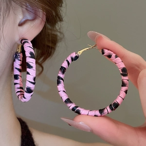 Gros plan de boucles d'oreilles créoles roses à motif léopard avec fermoir doré