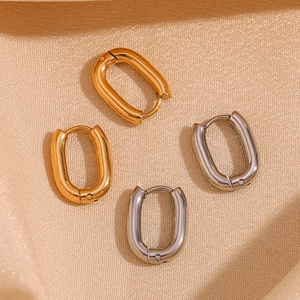 Close-up of minimalist oval hoop earrings in polished gold and silver steel finishes