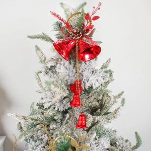Christmas tree topper with red bells, pine cones, and plaid ribbon hanging on snowy branch