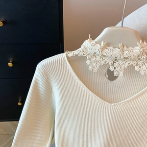 Détail de la découpe en cœur et bordure en dentelle sur un pull en maille crème