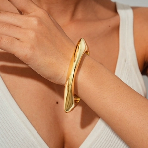 Macro shot of gold organic irregular lava cuff bracelet on female wrist with ribbed sleeve