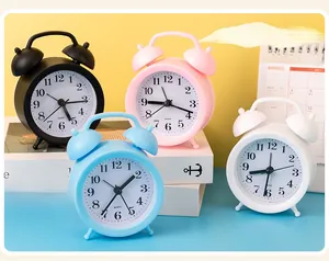 Close-up of small round twin bell quartz alarm clocks in pastel colors on a desk